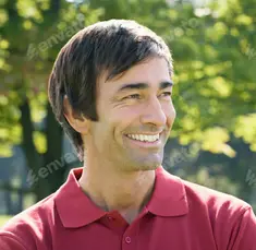 A man smiling outdoors in a red polo shirt.