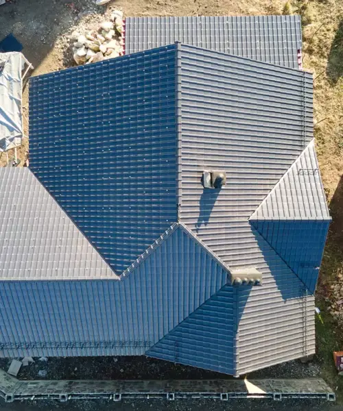 Aerial view of a house with a complex gray tiled roof.